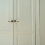 Białe, eleganckie drzwi dwuskrzydłowe z zamkiem w nowoczesnym wnętrzu