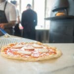 Kucharz wkłada pizzę do pieca w tradycyjnej portugalskiej kuchni