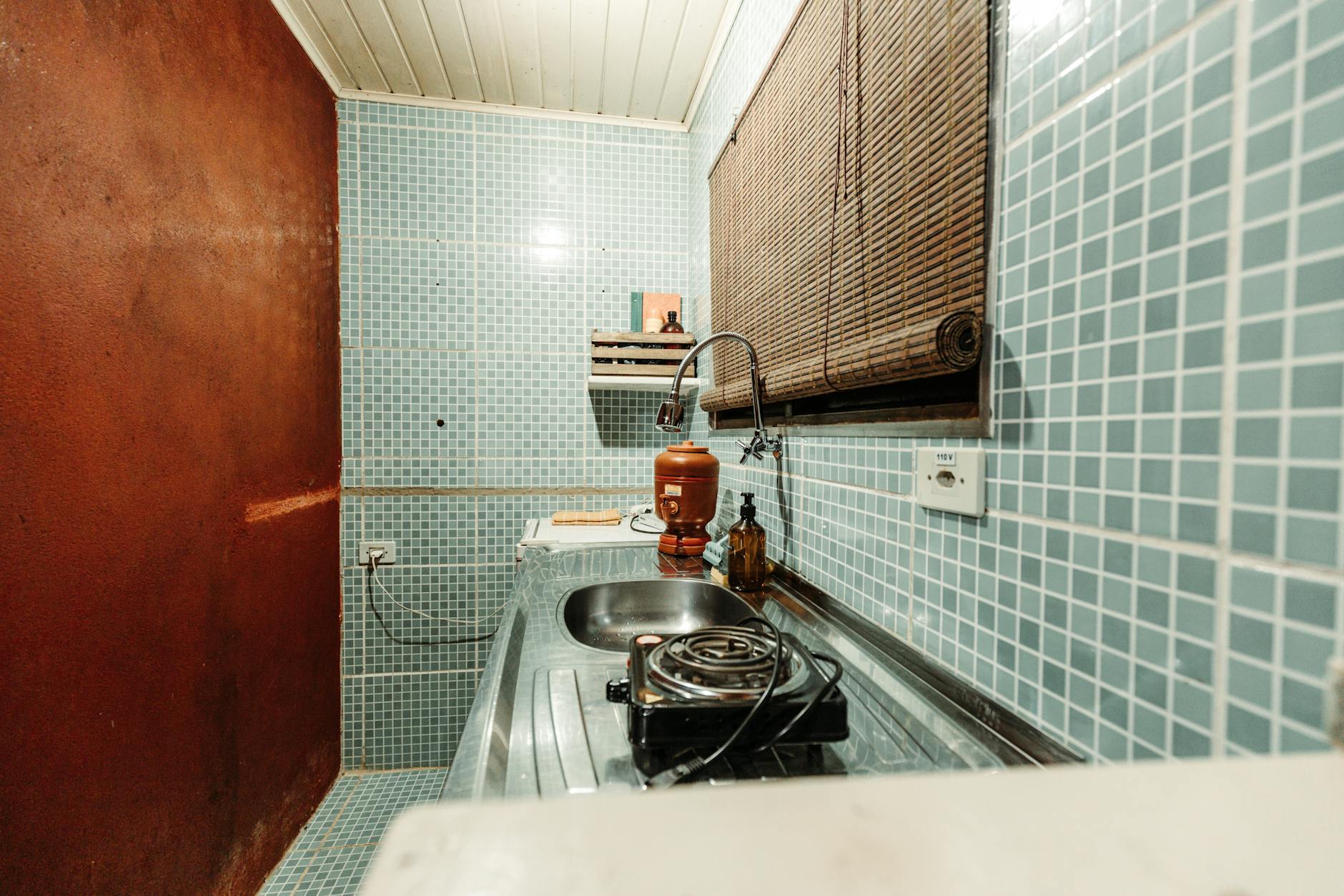 Mała kuchenka w kamienicy z niebieskimi płytkami i jednym palnikiem