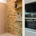 Mała kuchnia w kamienicy z ceglaną ścianą i nowoczesnym AGD