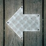 Metalowa strzałka na tle desek drewnianej podłogi