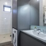 Nowoczesna łazienka w kamienicy z prysznicem, pralką i jasnym wystrojem