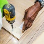 Ręczne wiercenie w drewnianej desce przy montażu nowej podłogi