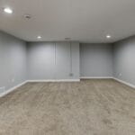 Jasna piwnica z szarymi ścianami i miękką wykładziną na podłodze