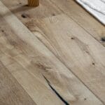 Jasne panele laminowane obok beżowego, plecionego dywanu