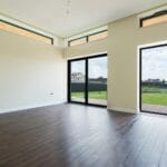 Jasny salon z dużymi oknami i drewnianą podłogą laminowaną