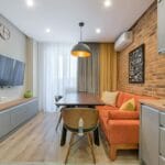 Salon w bloku z ceglaną ścianą, pomarańczową sofą i drewnianymi meblami