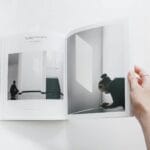 Dłoń trzyma otwartą fotoksiążkę o minimalistycznym układzie zdjęć