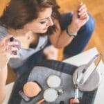 Młoda kobieta w pracy spryskuje szyję perfumami przy kosmetykach