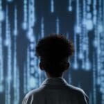 Chłopiec patrzy na cyfrowy ekran z danymi symbolizującymi technologię