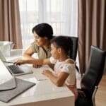 Mama pomaga córce w nauce online przy laptopie w domu